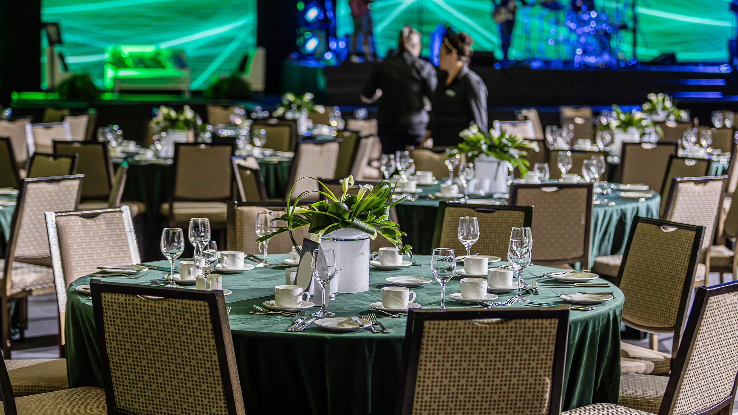 A banquet hall with green tables and chairs.
